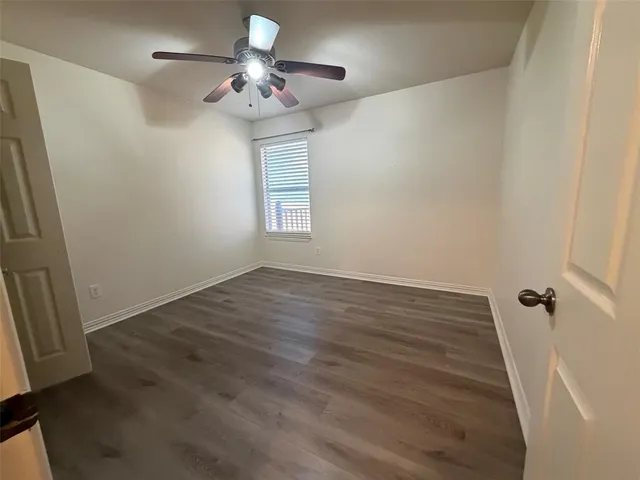a view of a room with wooden floor and a ceiling fan