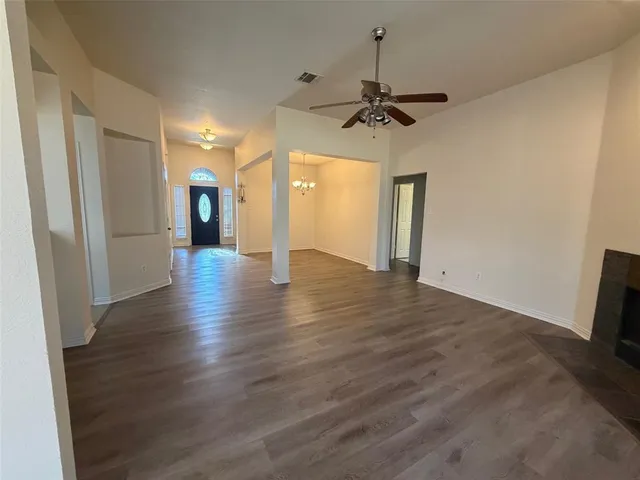 a view of an empty room with window and wooden floor