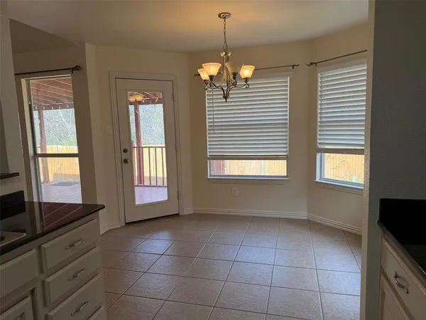 a view of an empty room with a window and chandelier