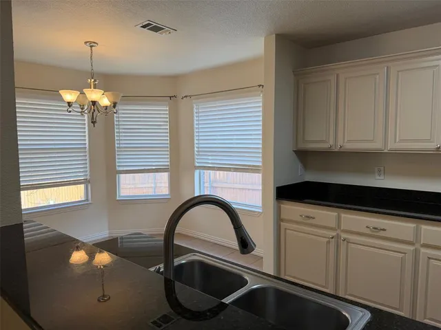 a kitchen with stainless steel appliances granite countertop a sink a stove and white cabinets