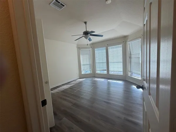 a view of empty room with wooden floor and fan
