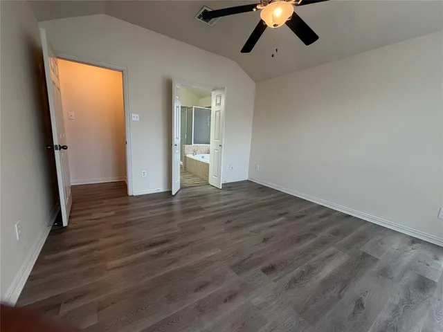 an empty room with wooden floor chandelier fan and windows