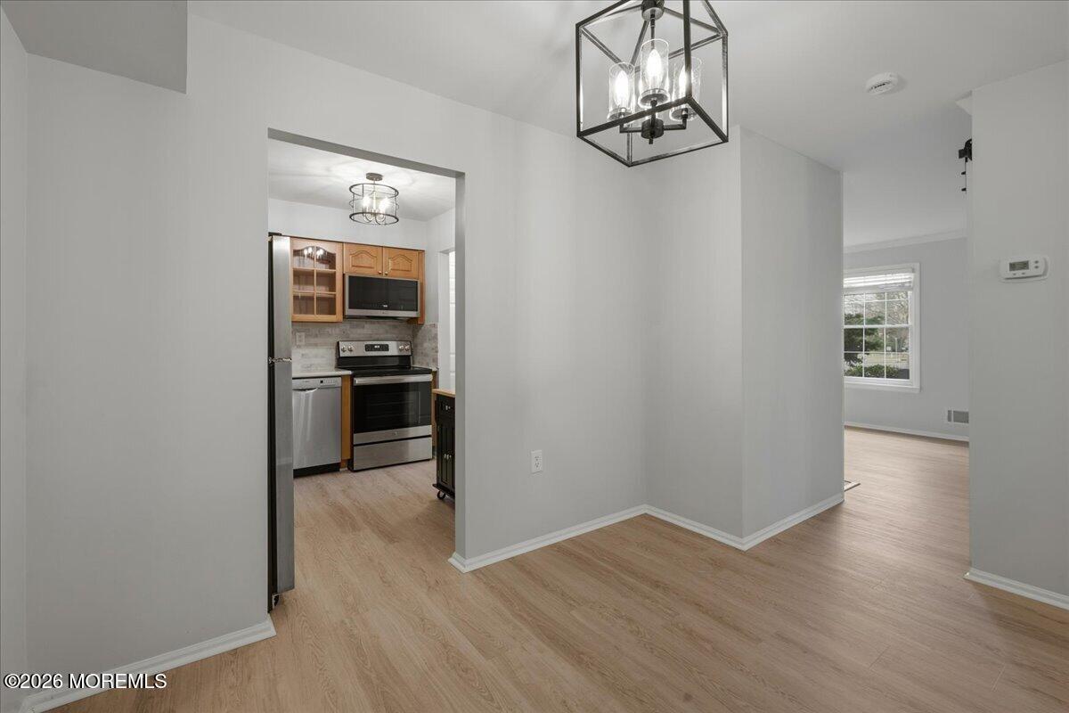 405 Wellington Place Matawan, NJ 07747 - Photo 11 of 29 an empty room with wooden floor a chandelier fan and windows