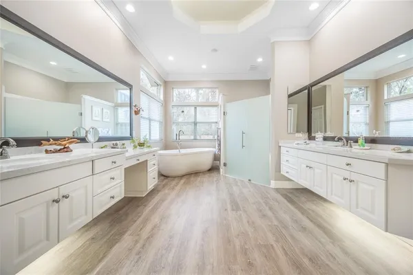 a spacious bathroom with a double vanity sink a large mirror and a bathtub