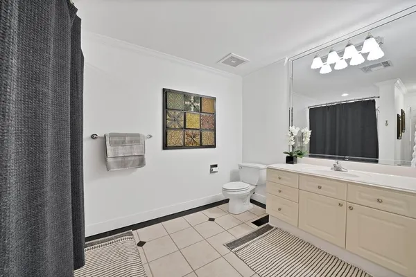 a spacious bathroom with a double vanity sink a toilet a mirror and vanity