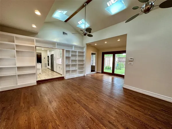 a view of empty room with wooden floor and fan