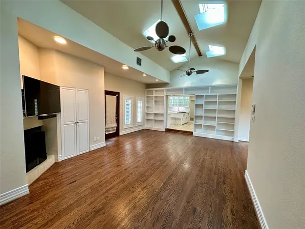 a view of an empty room with window and wooden floor