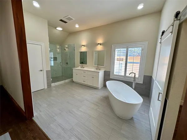 a spacious bathroom with a double vanity sink a large mirror and shower