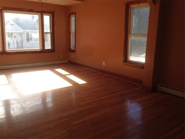 23 Emery Street Lowell, MA 01851 - Photo 2 of 5 an empty room with wooden floor and windows