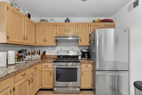 a kitchen with granite countertop a refrigerator stove and cabinets