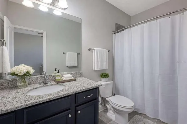 a bathroom with a granite countertop sink toilet and mirror