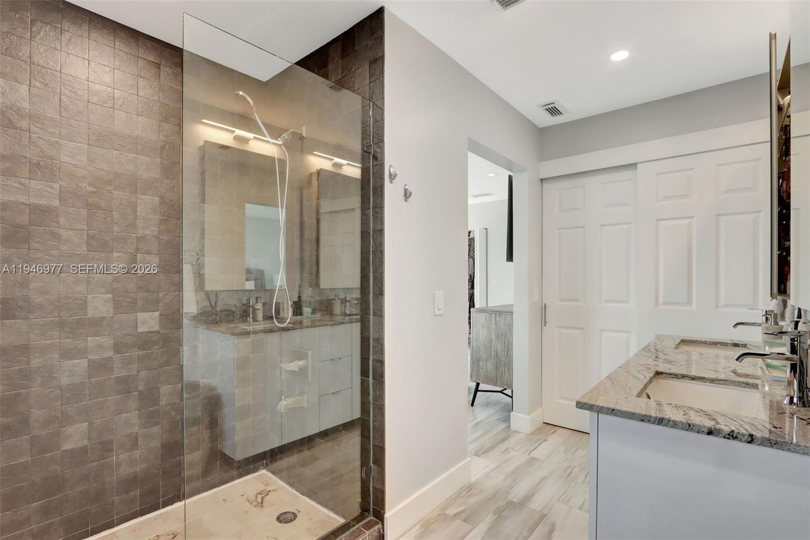 15481 Southwest 47th Terrace, Unit 15481 Miami, FL 33185 - Photo 25 of 29 a bathroom with a granite countertop sink a mirror and a shower