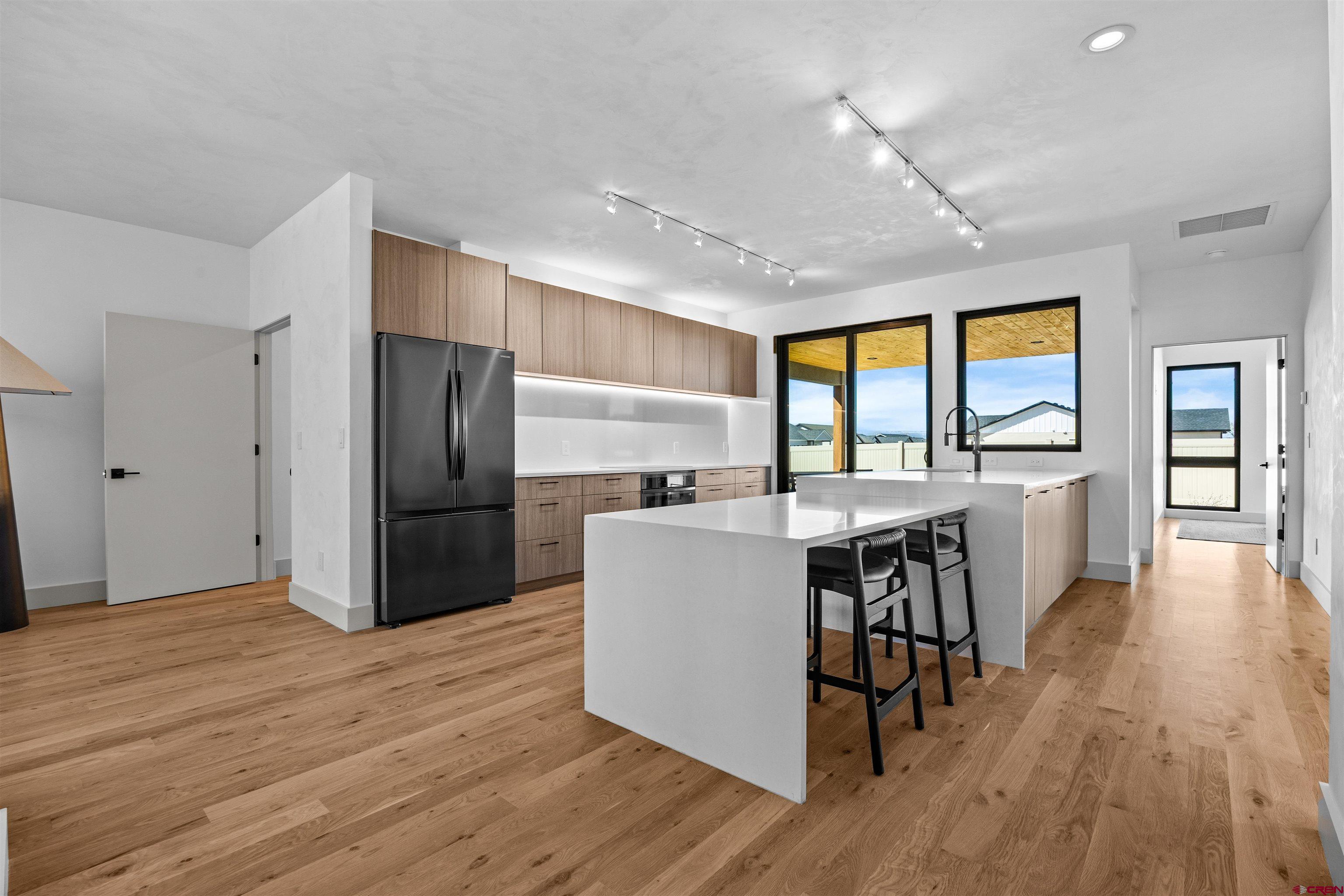 3435 Kestrel Loop Montrose, CO 81401 - Photo 9 of 34 a kitchen with stainless steel appliances a refrigerator a stove top oven a dining table and chairs with wooden floor