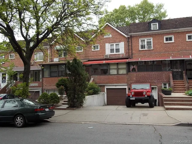 a front view of a house with cars parked on city street