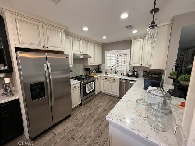 a kitchen with stainless steel appliances granite countertop a sink a stove a refrigerator and cabinets