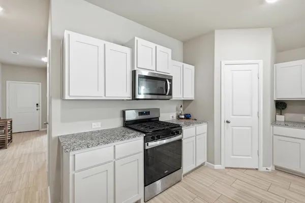 a kitchen with granite countertop white cabinets and stainless steel appliances