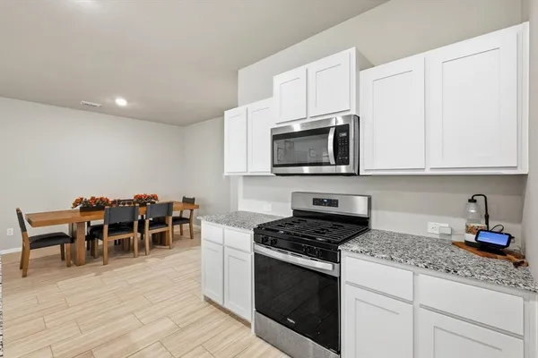 a kitchen with granite countertop stainless steel appliances a stove top oven a sink a counter space and cabinets
