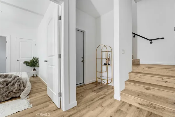 a view of a bedroom with wooden floor and white walls