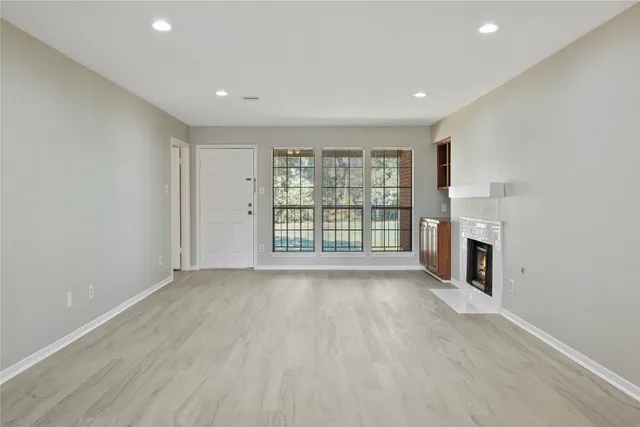a view of an empty room with a fireplace and a window