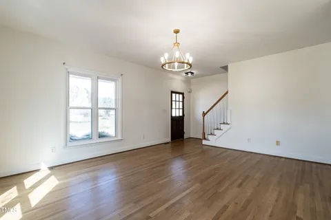 an empty room with wooden floor chandelier and windows