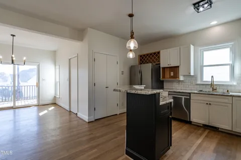 a kitchen with stainless steel appliances granite countertop a refrigerator a sink dishwasher a stove kitchen island and wooden floor