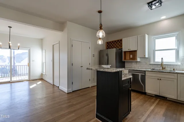 a kitchen with stainless steel appliances granite countertop a refrigerator a sink dishwasher a stove kitchen island and wooden floor