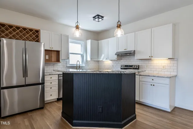 a kitchen with stainless steel appliances granite countertop a refrigerator a sink dishwasher a stove and white cabinets with wooden floor