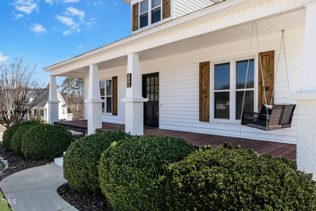 a view of a house with a small yard plants and large tree