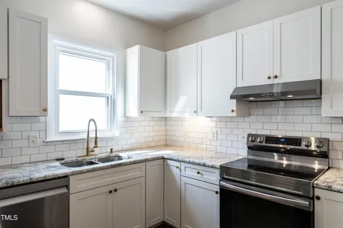 a kitchen with cabinets appliances a sink and a window