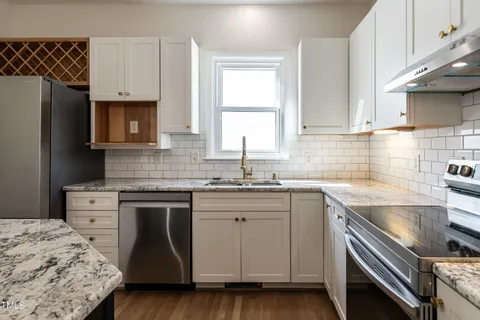 a kitchen with granite countertop a sink stainless steel appliances and white cabinets