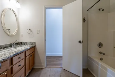 a bathroom with a granite countertop sink a mirror and a bathtub