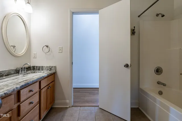 a bathroom with a granite countertop sink a mirror and a bathtub