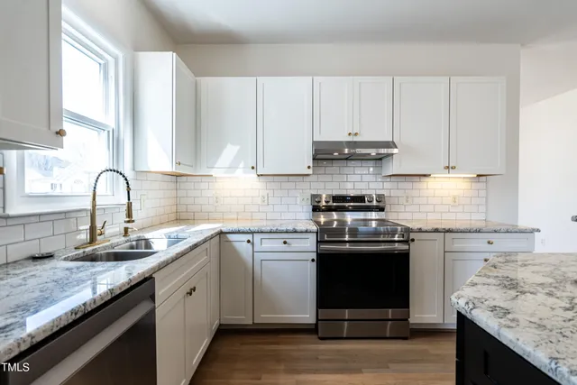 a kitchen with granite countertop a sink stove and cabinets