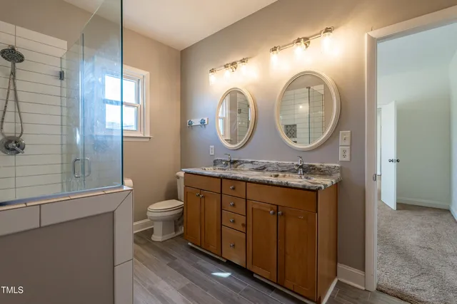 a bathroom with a granite countertop toilet a sink and a mirror