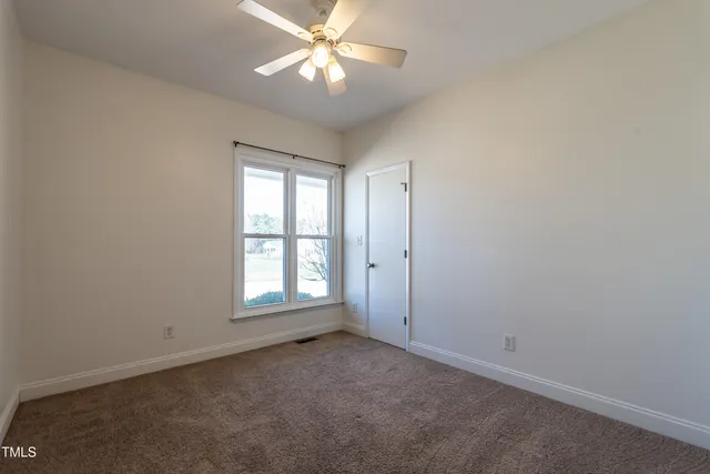 an empty room with a window and a fan