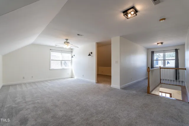 an empty room with windows and ceiling fan