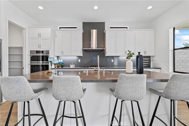a kitchen with stainless steel appliances granite countertop a dining table chairs and a refrigerator