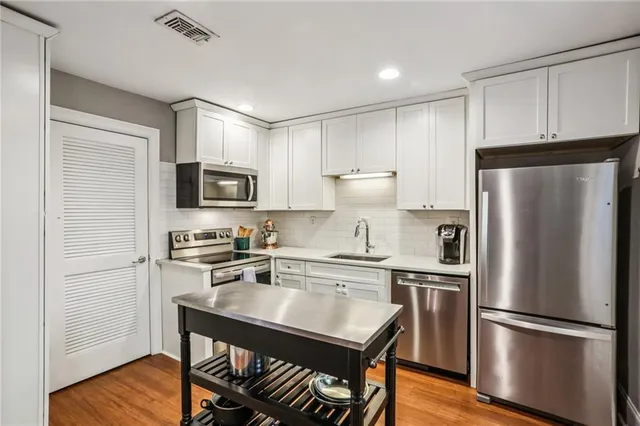 a kitchen with a refrigerator a microwave a sink and cabinets