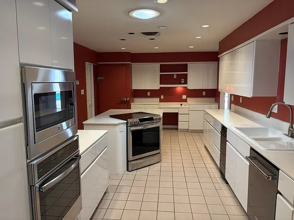 a room with a chair and white cabinets