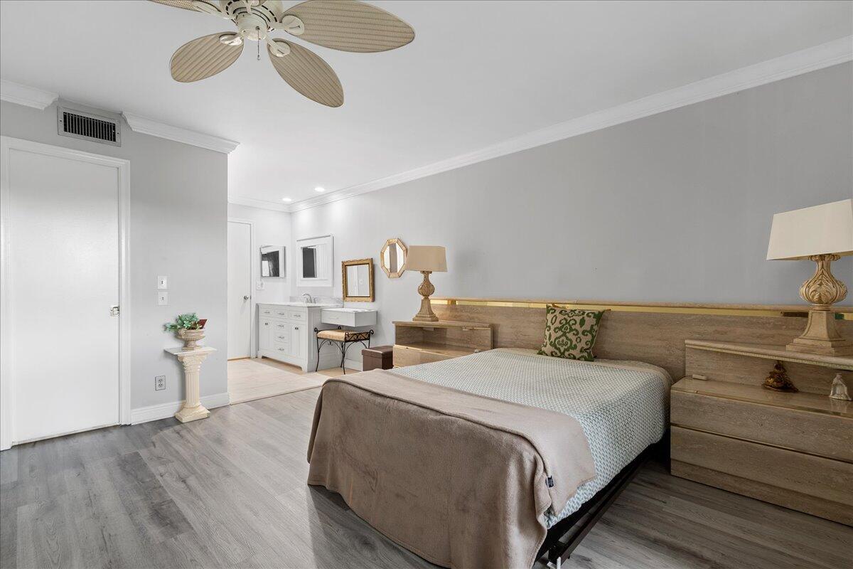 1395 Southwest 27th Avenue, Unit 103 Delray Beach, FL 33445 - Photo 23 of 26 a large bedroom with a bed and wooden floor