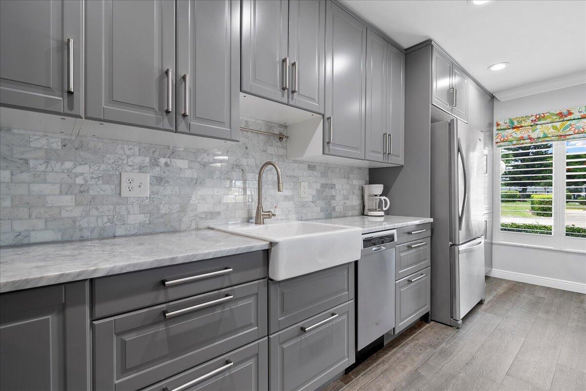 1395 Southwest 27th Avenue, Unit 103 Delray Beach, FL 33445 - Photo 9 of 26 a kitchen with stainless steel appliances granite countertop a sink stove and cabinets