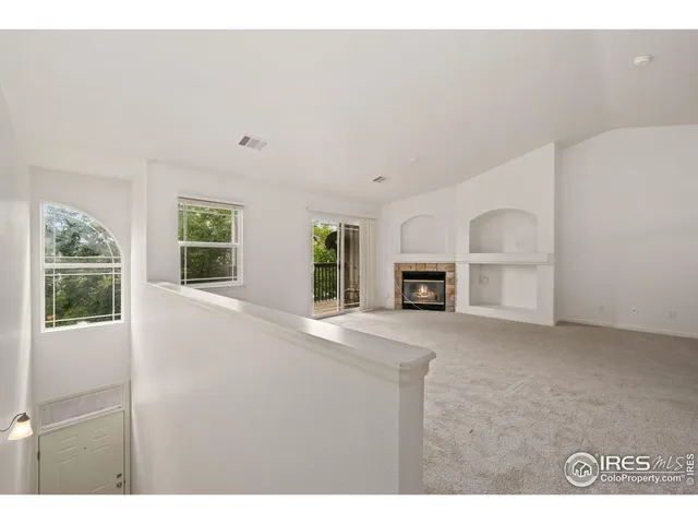 a view of an empty room with fireplace and windows