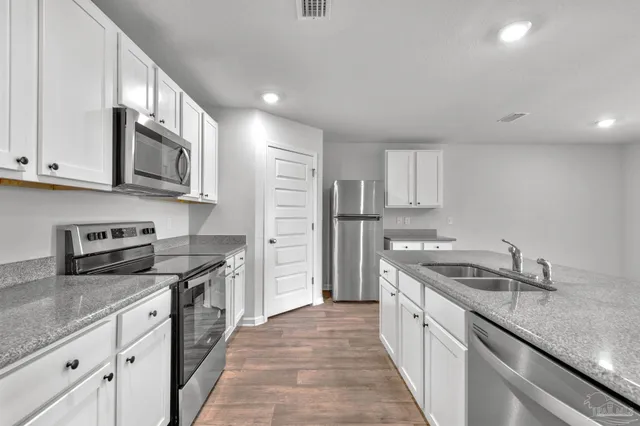 a kitchen with stainless steel appliances granite countertop a sink stove and refrigerator