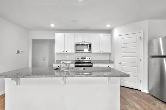 a kitchen with kitchen island a sink stainless steel appliances and cabinets
