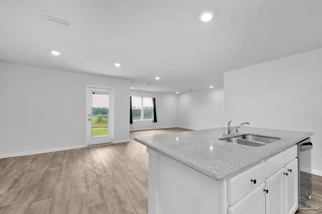 a view of a kitchen island a sink wooden floor and a living room