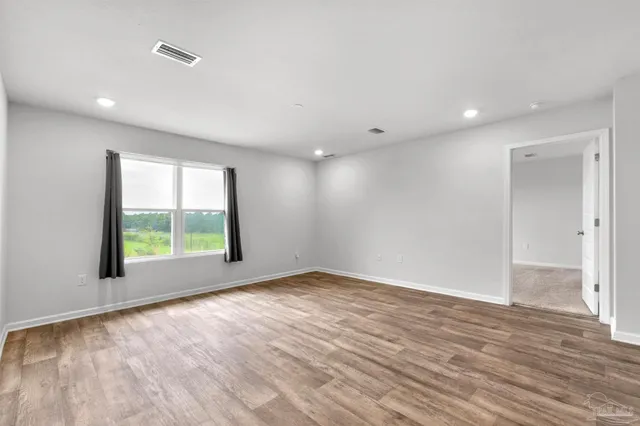 a view of an empty room with a window and wooden floor