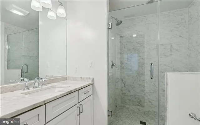 a bathroom with a granite countertop sink a mirror and shower