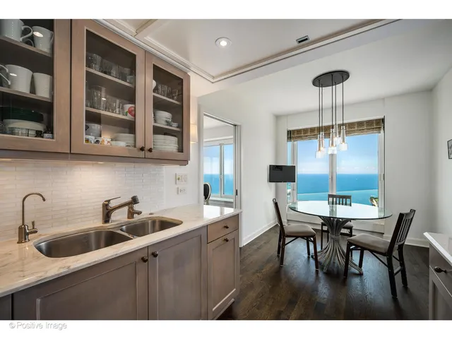 a kitchen with stainless steel appliances granite countertop a table chairs in it and wooden floors