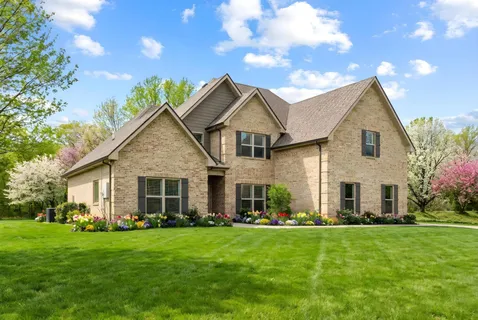 a front view of a house with a garden and yard
