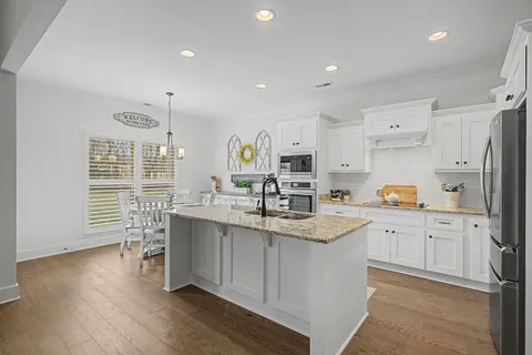 a kitchen with stainless steel appliances granite countertop a lot of counter space and wooden floors